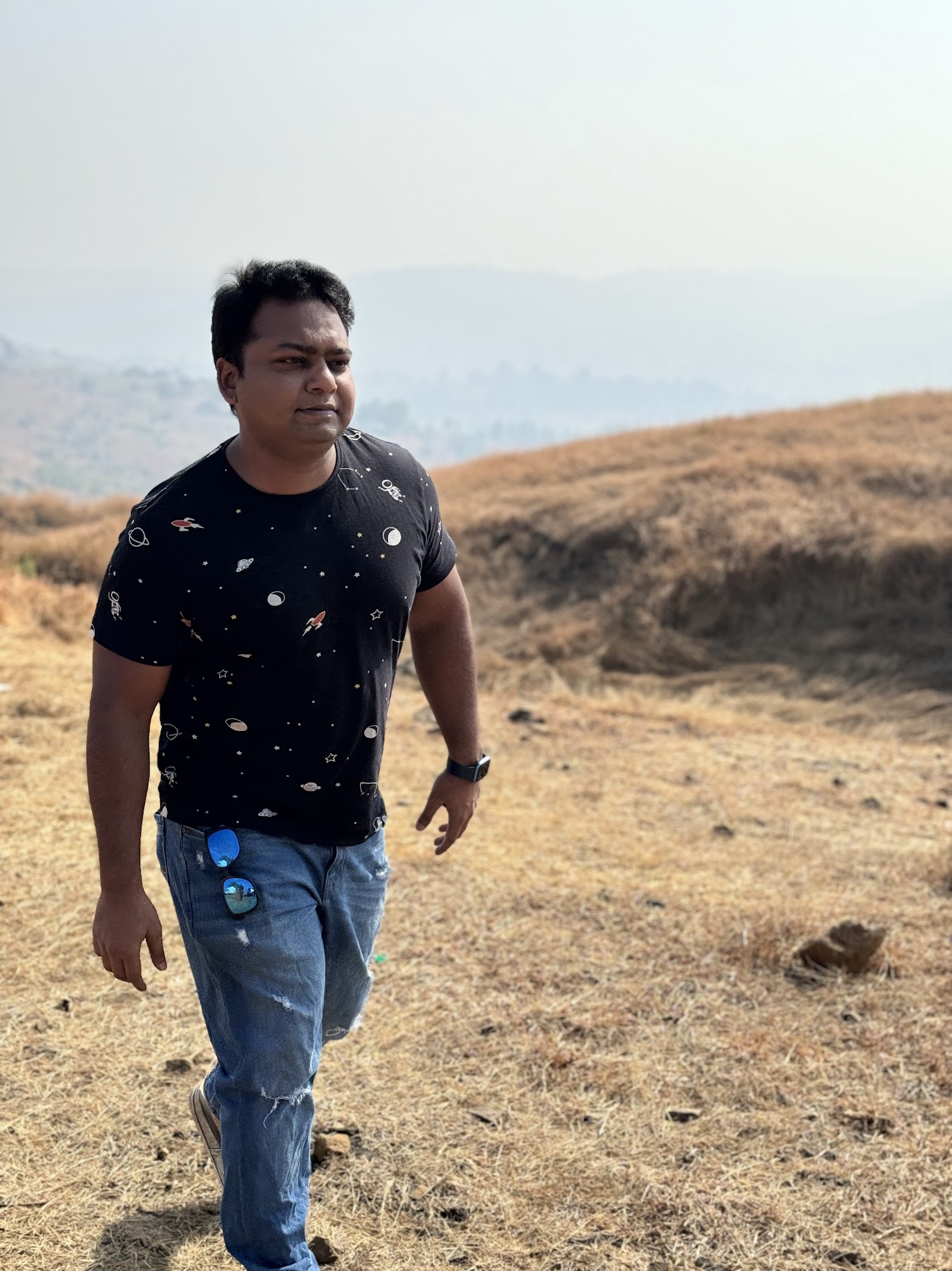 Suchay walking outdoors against an open hillside